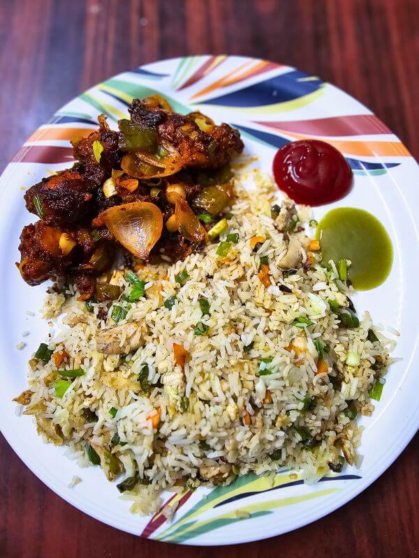 A plate of chicken fried rice with chili chicken, a perfect post-workout refeed meal.