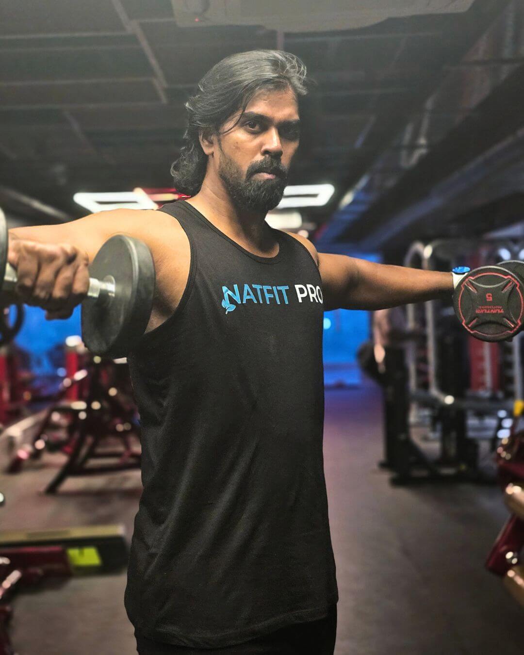 lateral-raise-dumbbell-gym-natfitpro Man doing lateral raise with dumbbells for shoulder workout at Natfit Pro gym